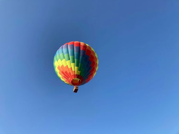 A colorful hot air balloon floats against a clear blue sky, creating a vibrant and serene scene.