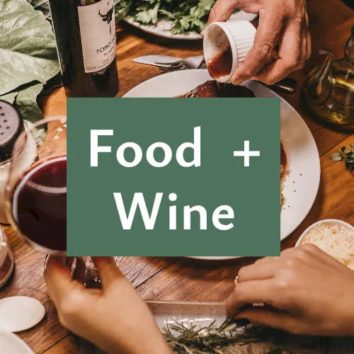 A dinner table with friends sharing wine as &ldquo;Food + Wine&rdquo; text overlays the scene.