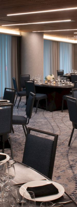 A banquet hall set up with round tables, chairs, elegant table settings, and dim lighting creates a formal dining atmosphere.